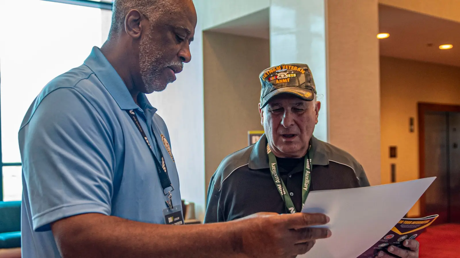 Two men discuss paperwork.