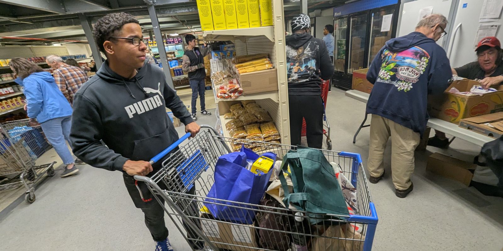 Spc. Oscar Moore helps load up a patron’s cart at the Veterans Food Pantry in Watertown.  Photo by Mike Strasser, Fort Drum Garrison Public Affairs