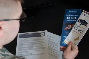 Soldier reads GI Bill brochures.