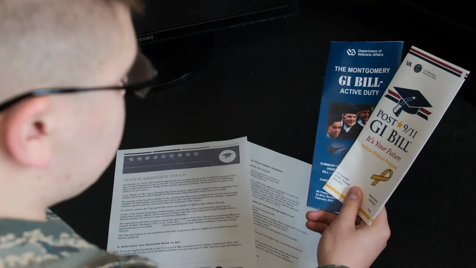 Soldier reads GI Bill brochures.