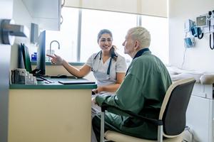 A woman talks with her doctor while they look at a desktop computer.