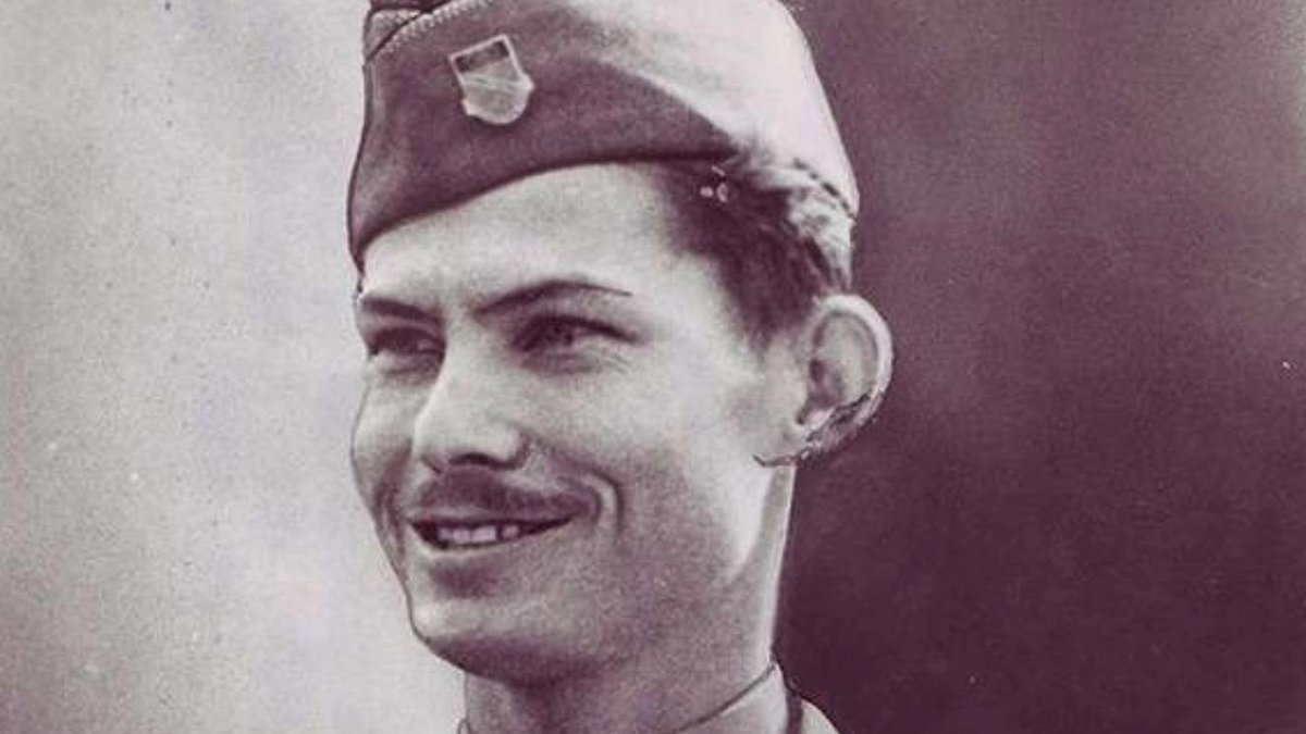 Army medic in dress uniform smiling, wearing a garrison cap with insignia.