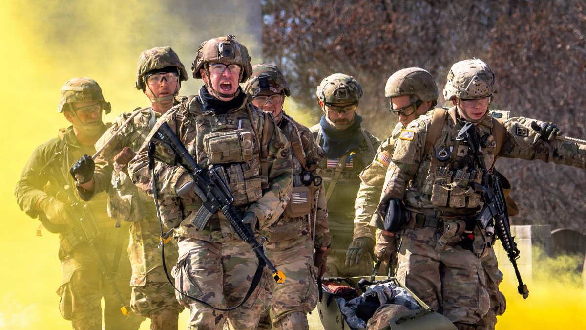 In training a group of soldiers escort two medics and a body on a gurney through smoke and gunfire.