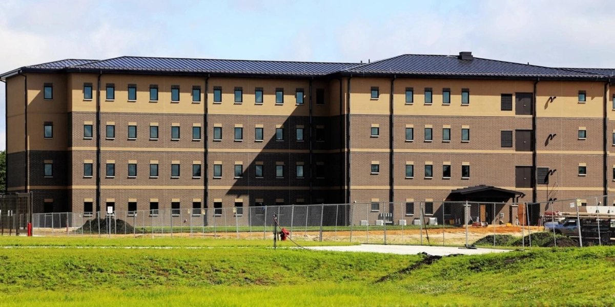 New Army barracks building with fenced perimeter and construction materials on site