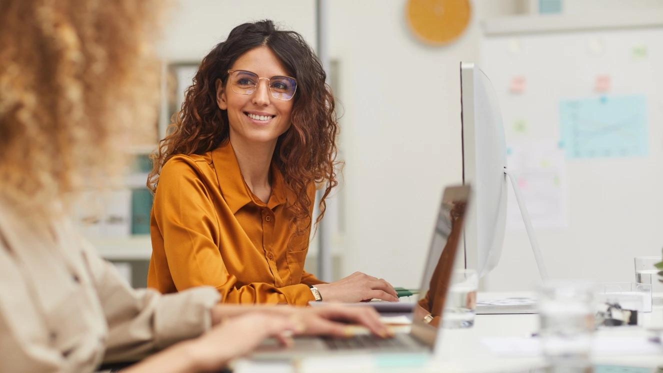 Military spouses working at office desks, collaborating on defense economy projects.