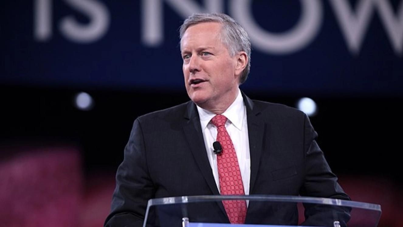 Mark Meadows speaking at podium in suit and red tie during public event