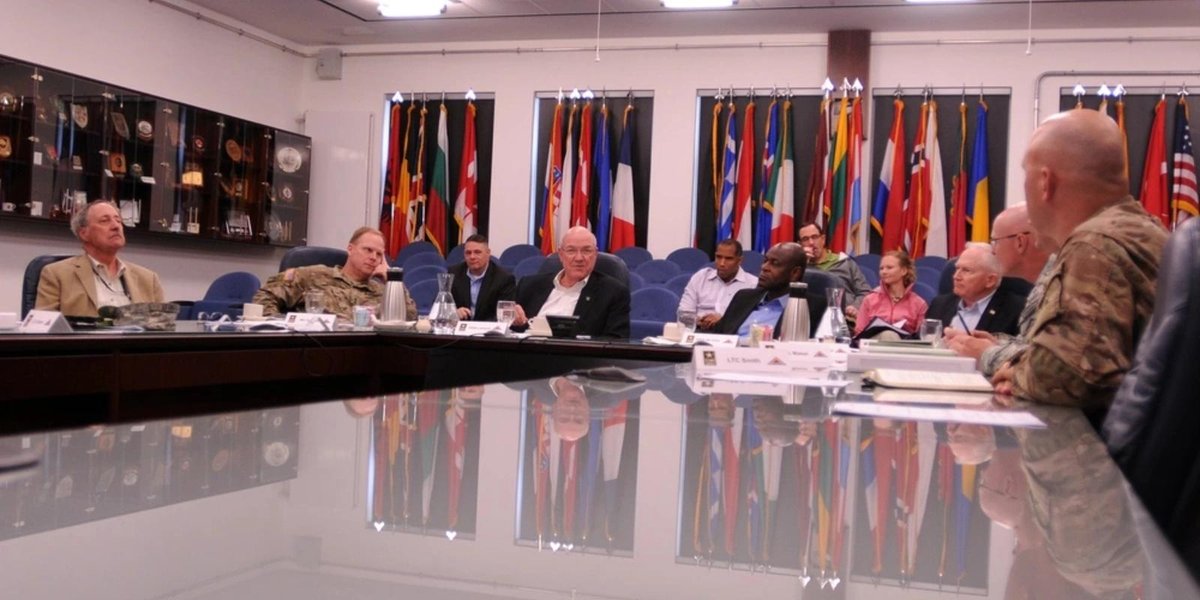 Army officers in a conference room with international flags discussing political preferences