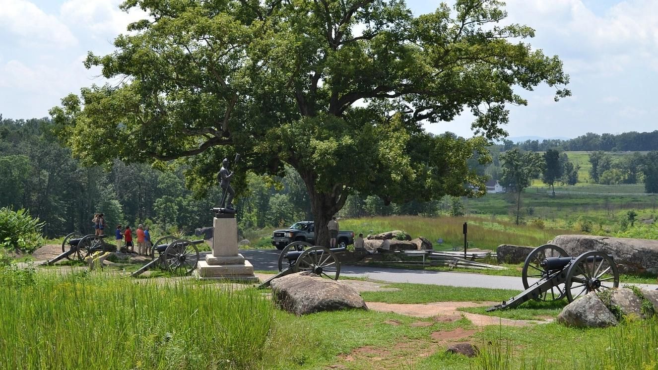 Devil's Den at Gettysburg with Civil War cannons and monument under a large oak tree