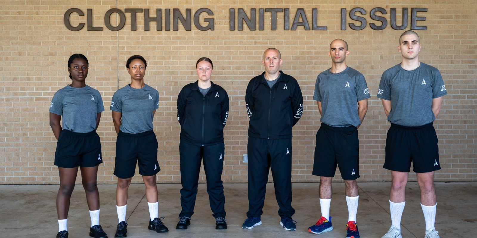 Space Force servicemembers stand in a line wearing new Space Force athletic clothing.