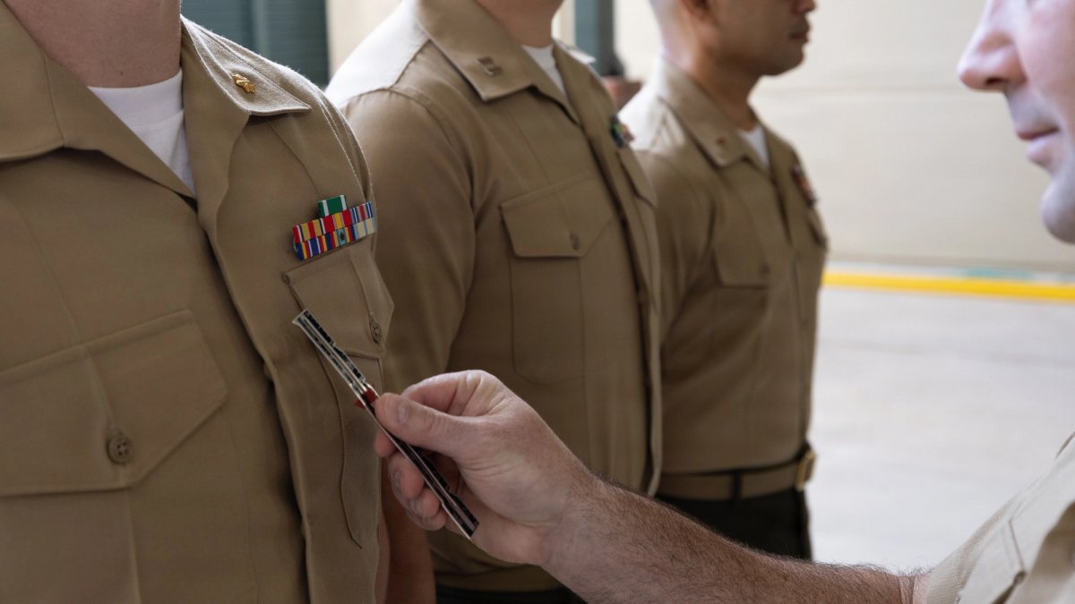 Close-up of a hand holding a ruler during inspection of soldiers standing in a line.