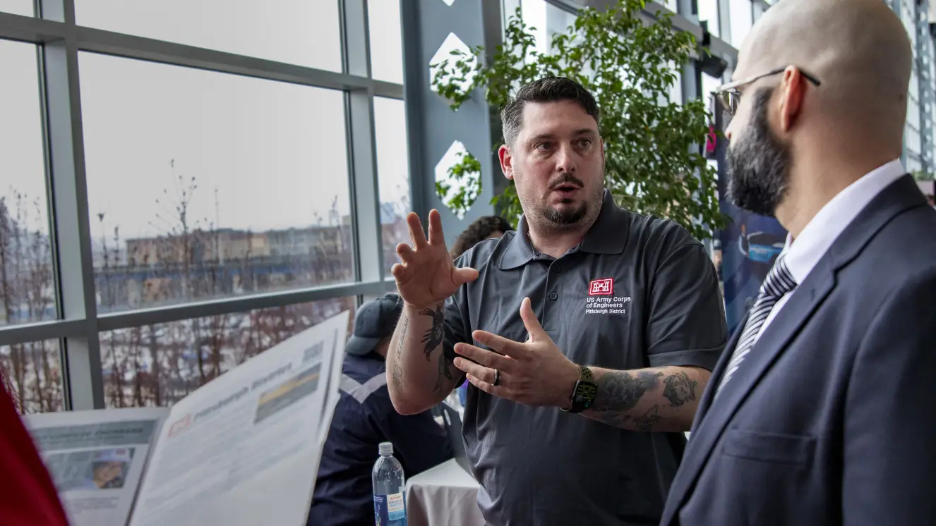 Scott Reed, the lead recruiter for the U.S. Army Corps of Engineers Pittsburgh District, talks to a prospective recruit about job benefits offered by federal employment during a military community hiring event at Acrisure Stadium in Pittsburgh.