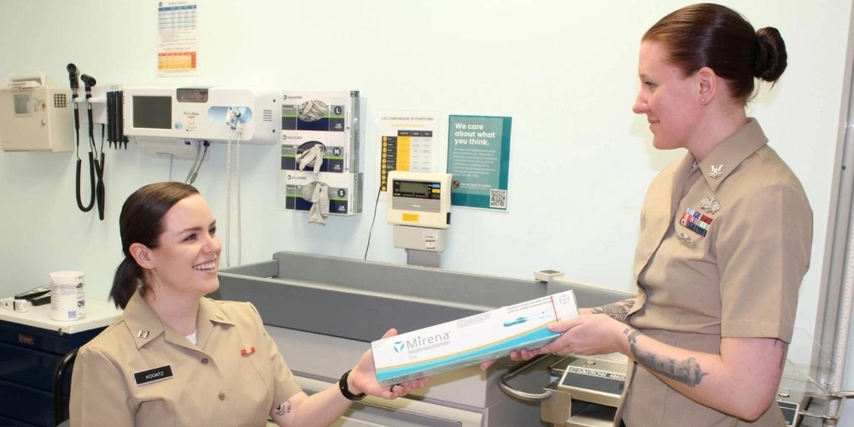 Two Navy personnel in a medical office discussing Mirena birth control device.