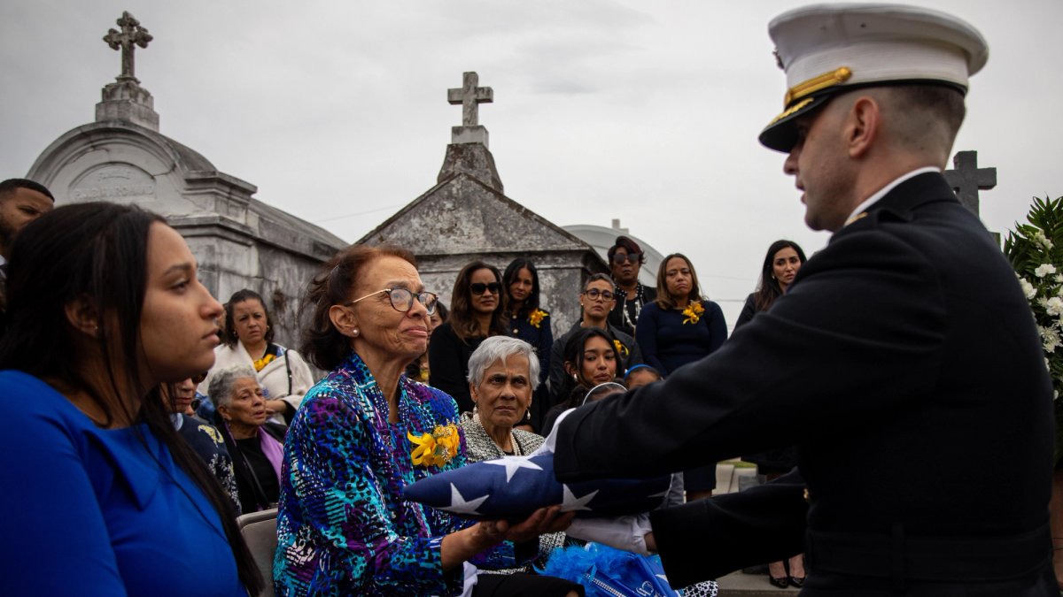A wife is handed a flag at a military funeral.