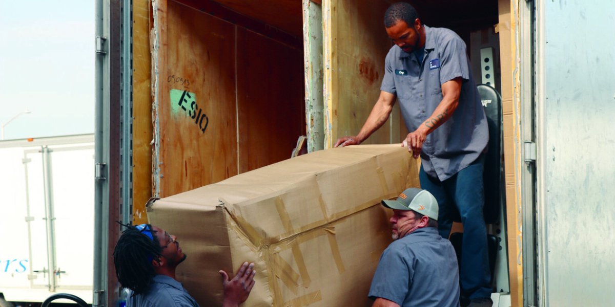 Movers deliver household goods out of a moving truck.