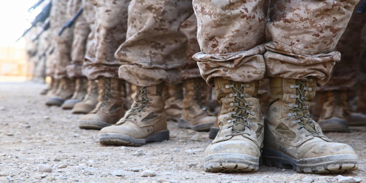 U.S. service members standing in formation, showing rows of combat boots and camouflage uniforms.