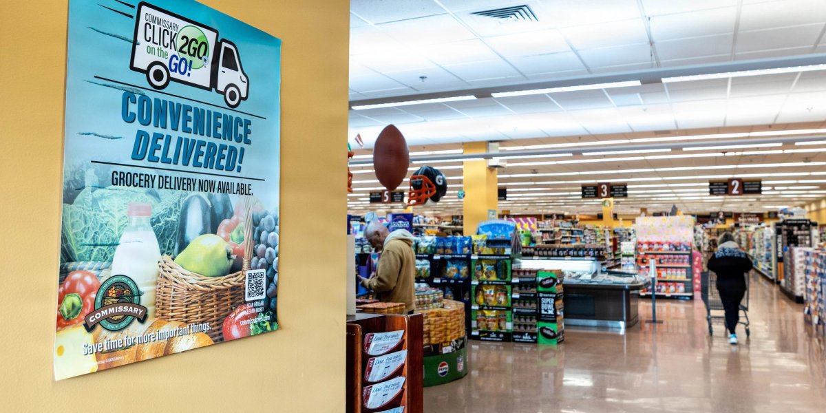 Entry to a supermarket with signage promoting home delivery.
