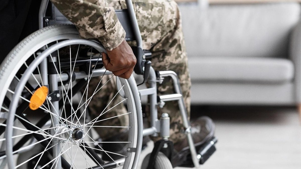 Veteran in camouflage uniform sitting in a wheelchair indoors