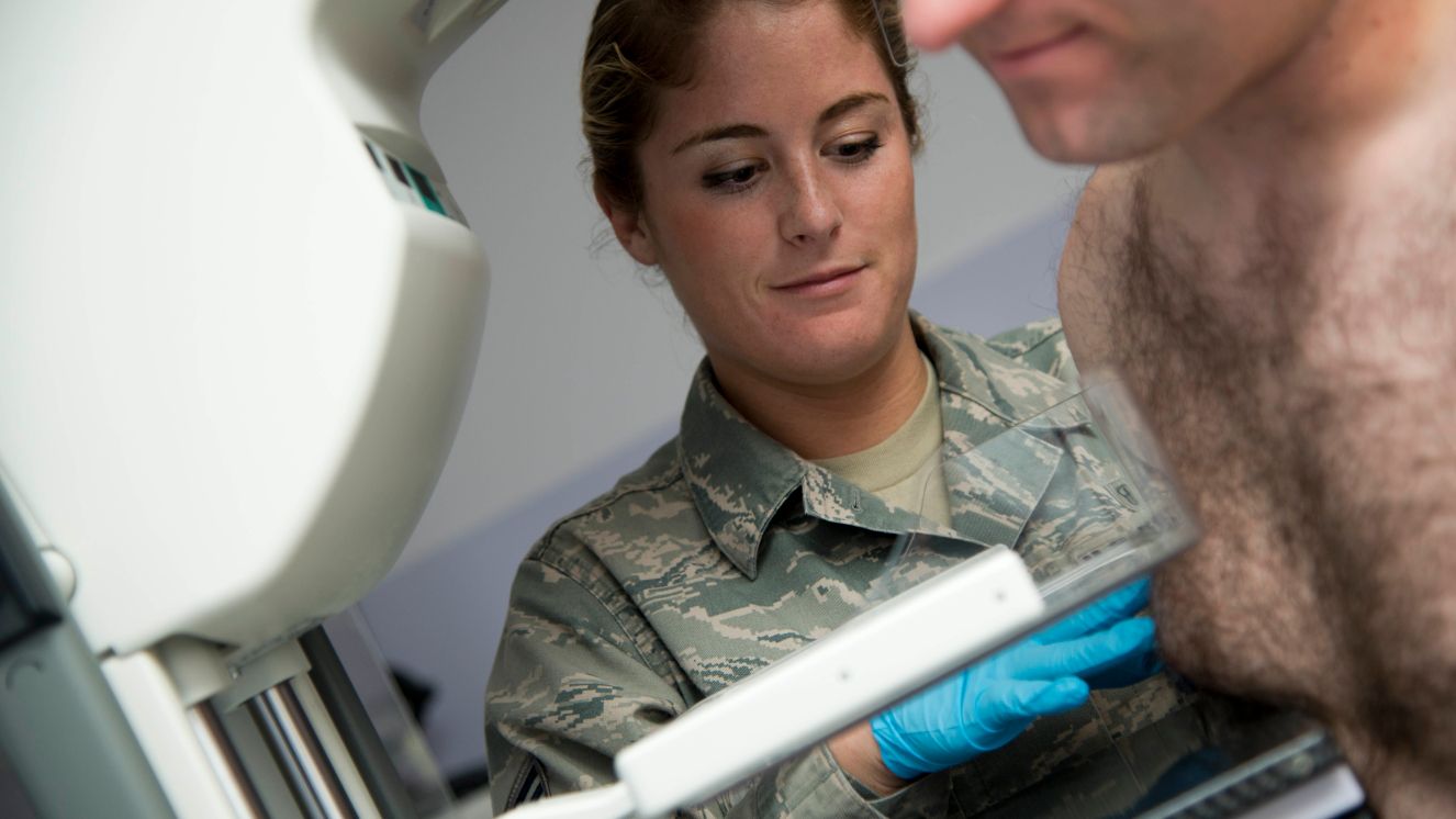 Senior Airman Elisabeth Stone compresses a male patient's breast tissue during a baseline screening of mammogram at Joint Base Elmendorf-Richardson, Alaska, Oct. 20, 2014. (U.S. Air Force photo/Staff Sgt. Sheila deVera)
