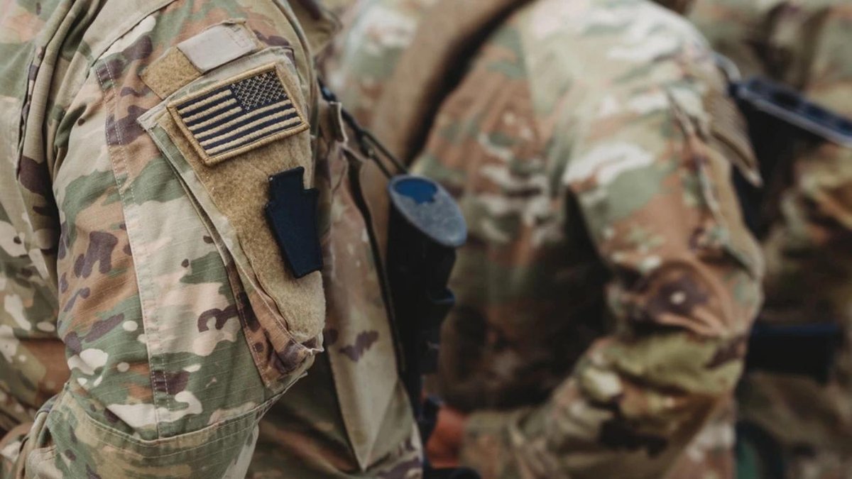 Army soldiers in camouflage with American flag patches on uniforms.
