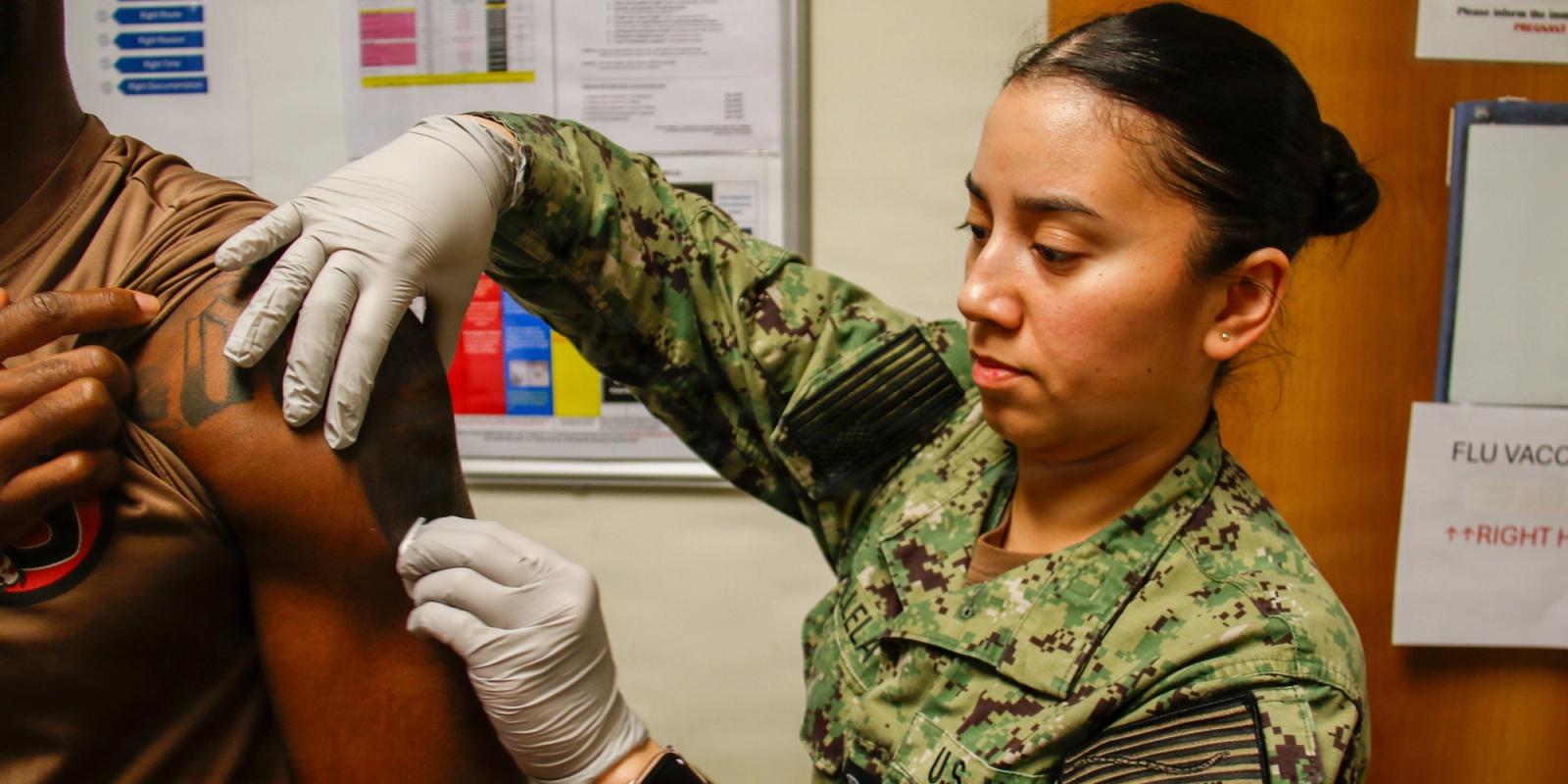 Medic administers a flu shot into a soldier’s arm.