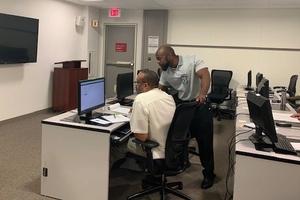 An instructor trains a worker at a computer.