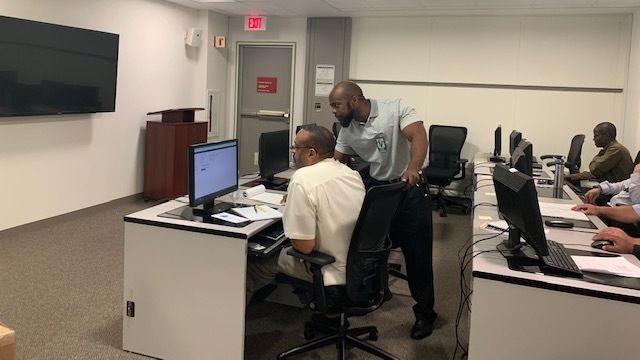 An instructor trains a worker at a computer.