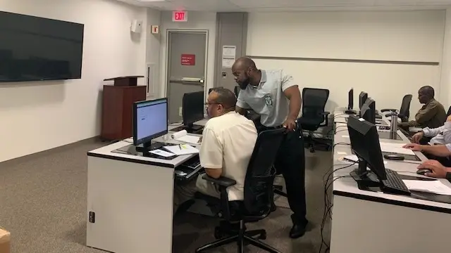 An instructor trains a worker at a computer.