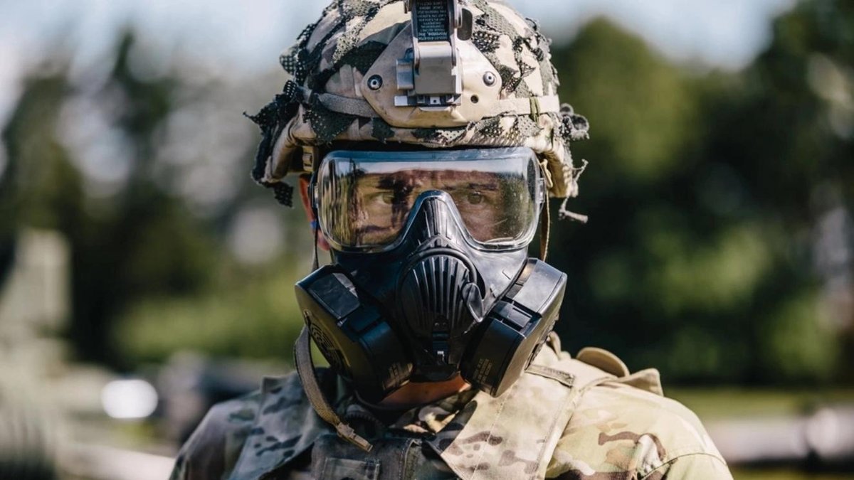 Soldier wearing MOPP gear and gas mask outdoors, focusing on protective equipment.