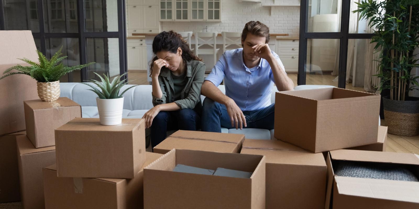 Tired couple in despair during a move surrounded by boxes.