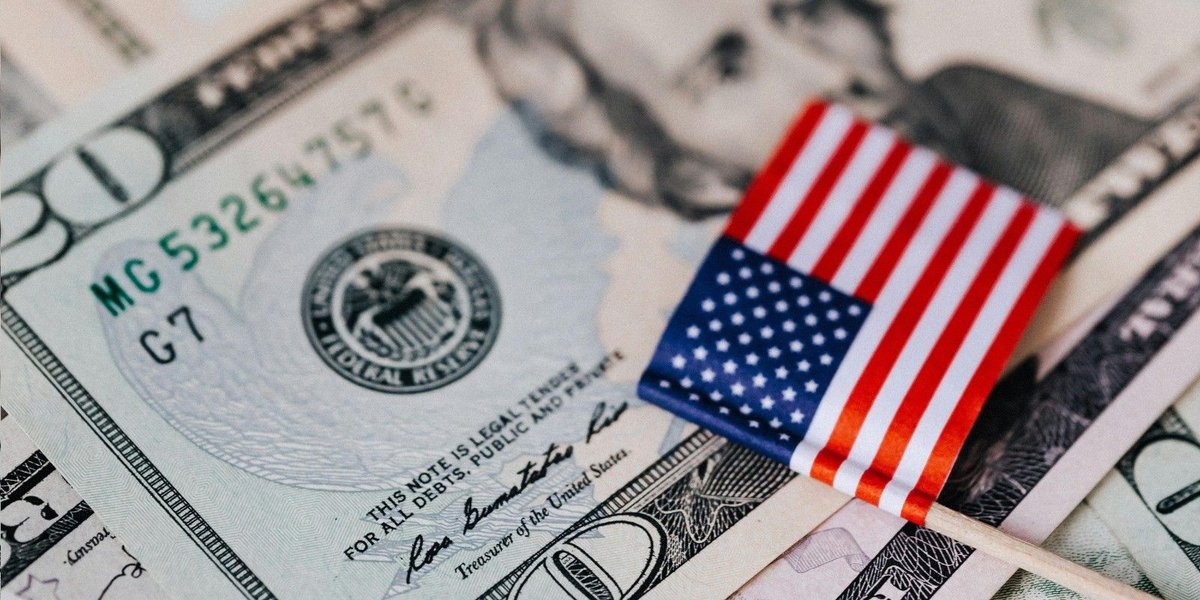 American flag on U.S. currency, symbolizing economic decisions impacting military pay.
