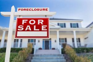 Close-up picture of a Foreclosure For Sale sign in front of a house.