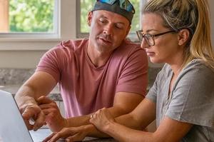 Marine and his wife are looking at a website on a laptop.