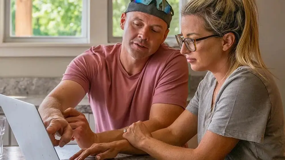 Marine and his wife are looking at a website on a laptop.