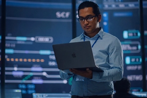 A cybersecurity analyst works on a laptop.