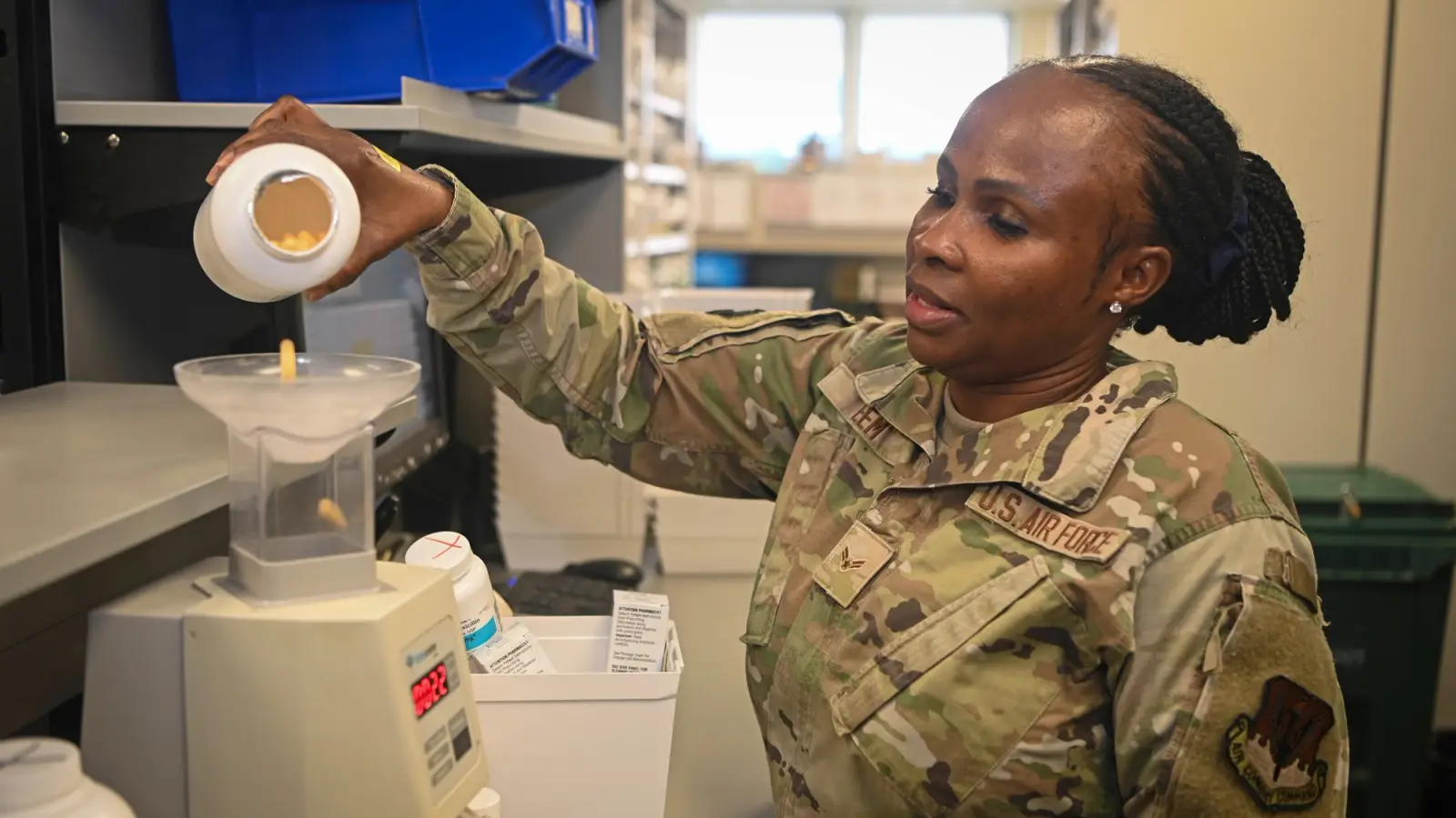 A uniformed pharmacist pours pills into a pill counter.