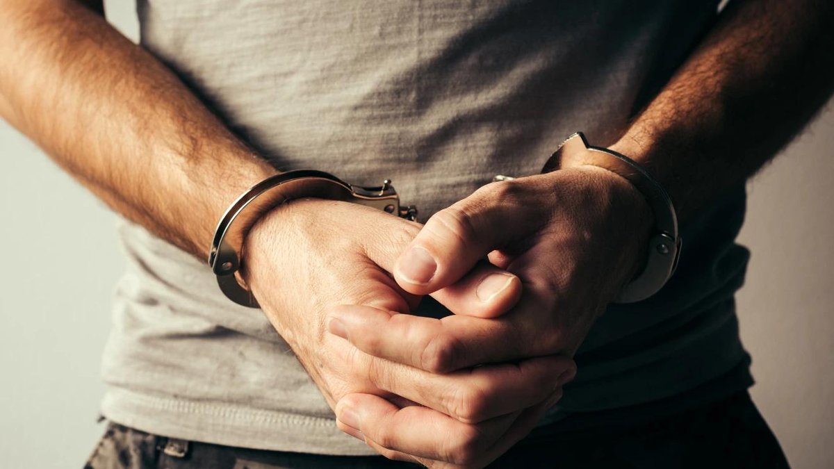 Incarcerated person in handcuffs wearing a gray shirt, highlighting challenges for veterans.