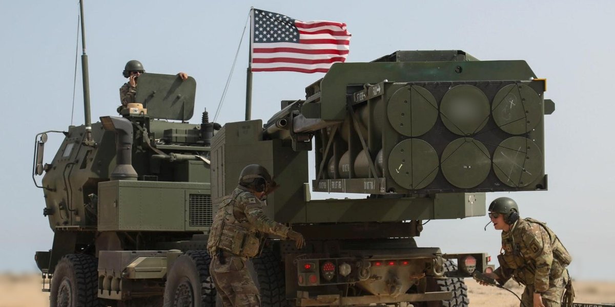 Soldiers in the desert working on a missile launcher.