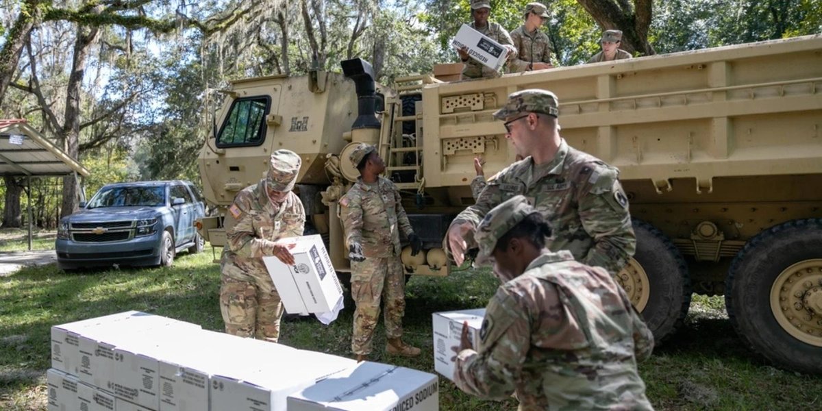 National Guard soldiers distributing relief supplies from military truck in hurricane-affected area.