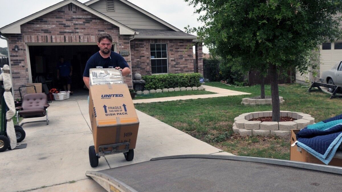 A mover rolls boxes onto a truck.