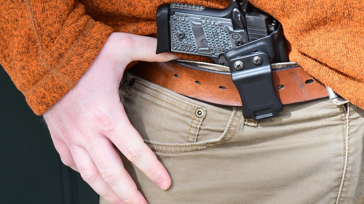 Close-up of a hand on a firearm in a waistband.