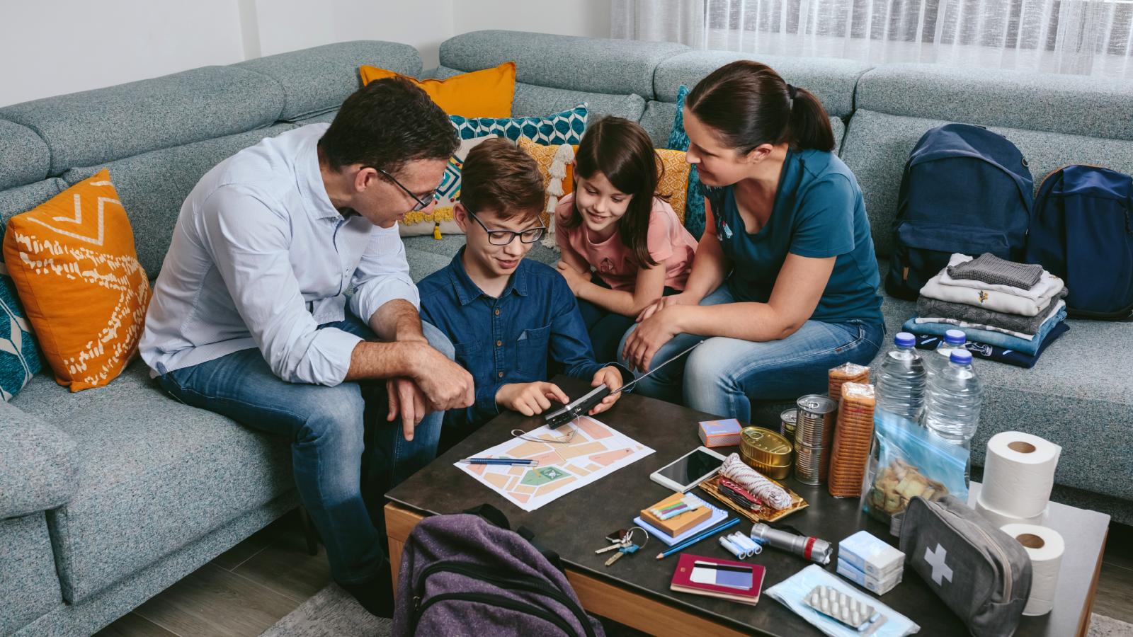A family sits around a table with emergency supplies.