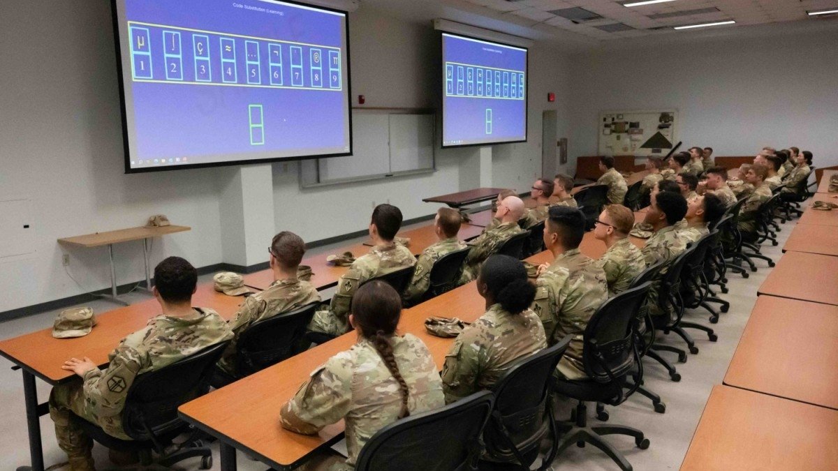 A room full of soldiers look at screens filled with technical symbols.
