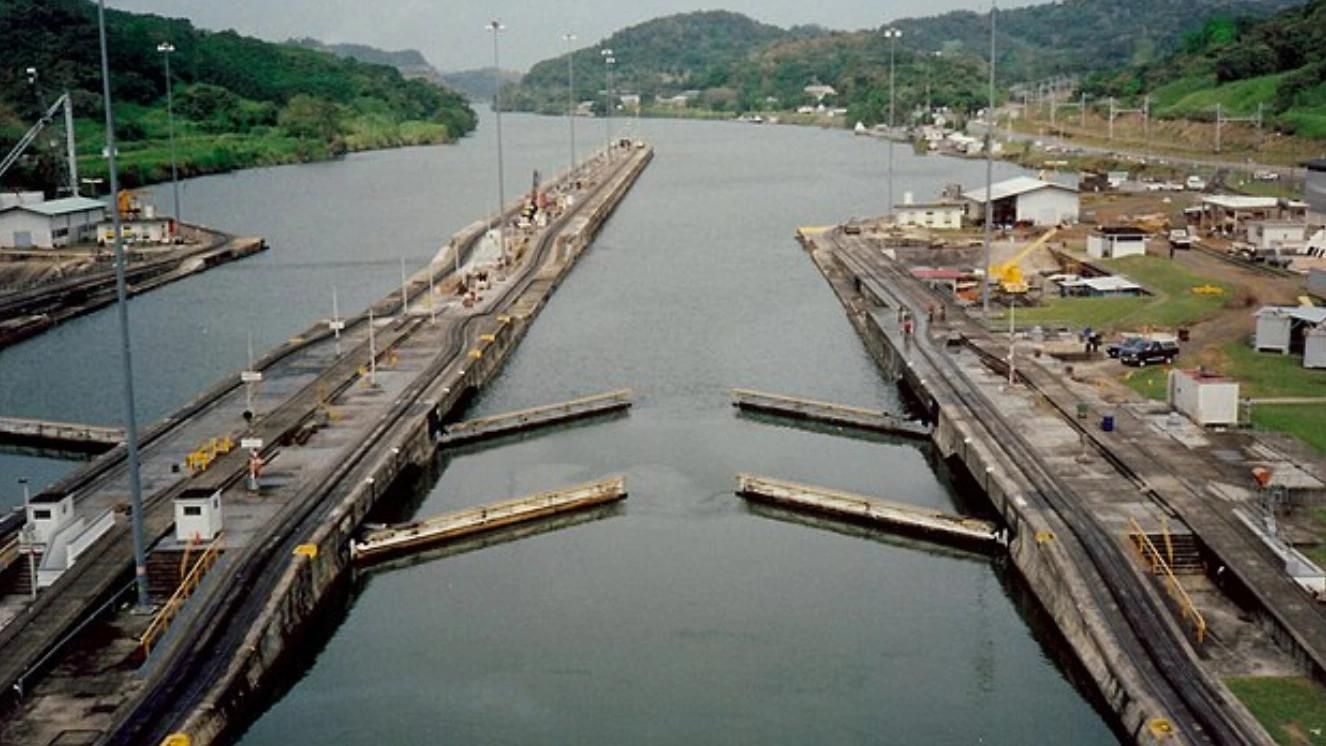 Panama Canal locks with surrounding facilities and hilly landscape in the background.