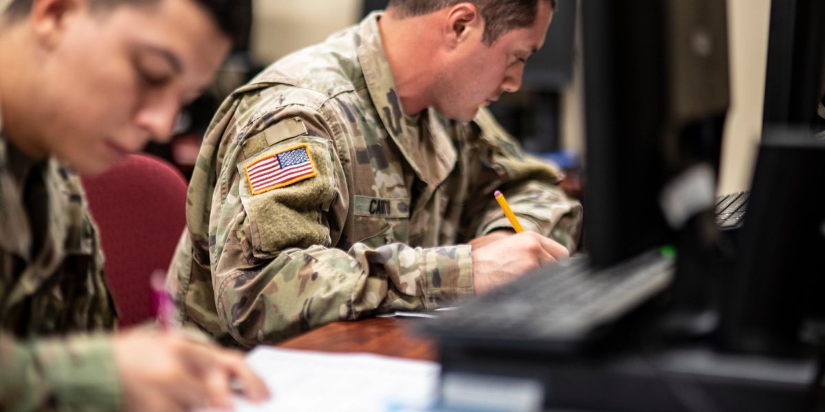 Two servicemen study and take notes.