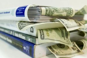 Textbooks stacked with money.