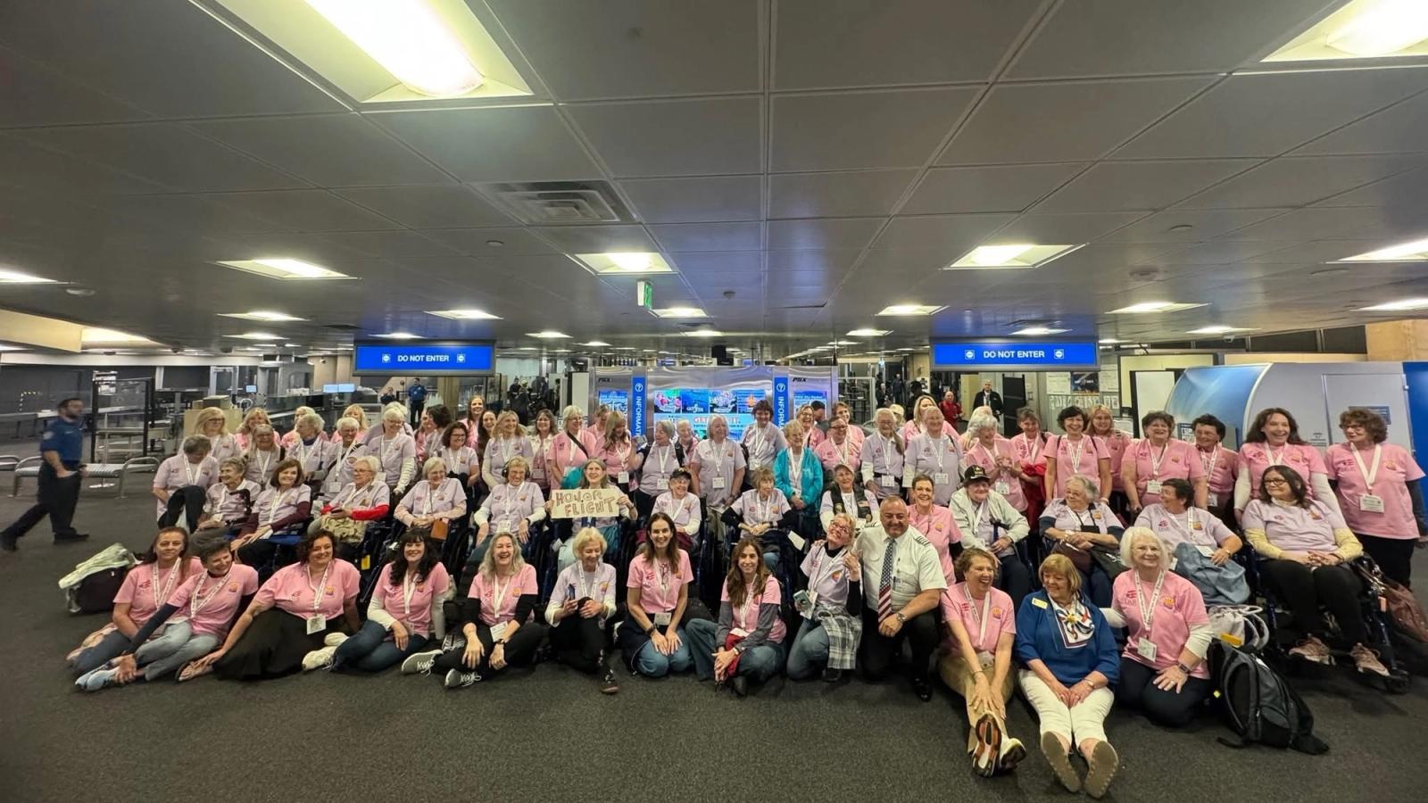 The entire group of veterans in the All-Woman Honor Flight pose with the pilot.