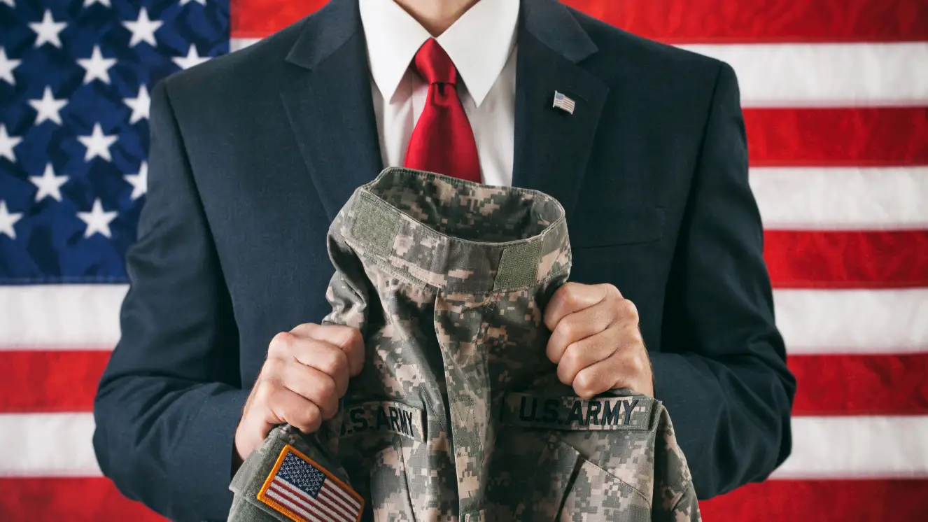 A man in a suit holding a military uniform.