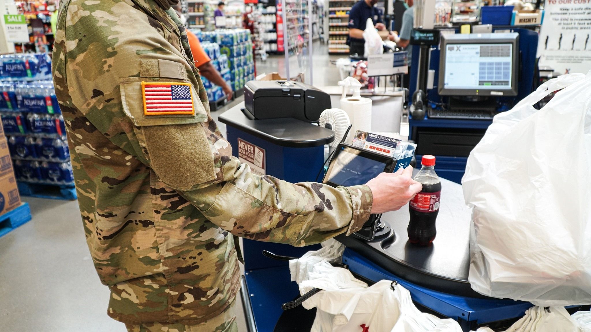 A soldier uses a debit card in a grocery store.