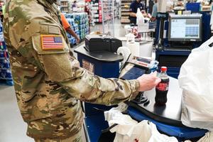 A soldier uses a debit card in a grocery store.