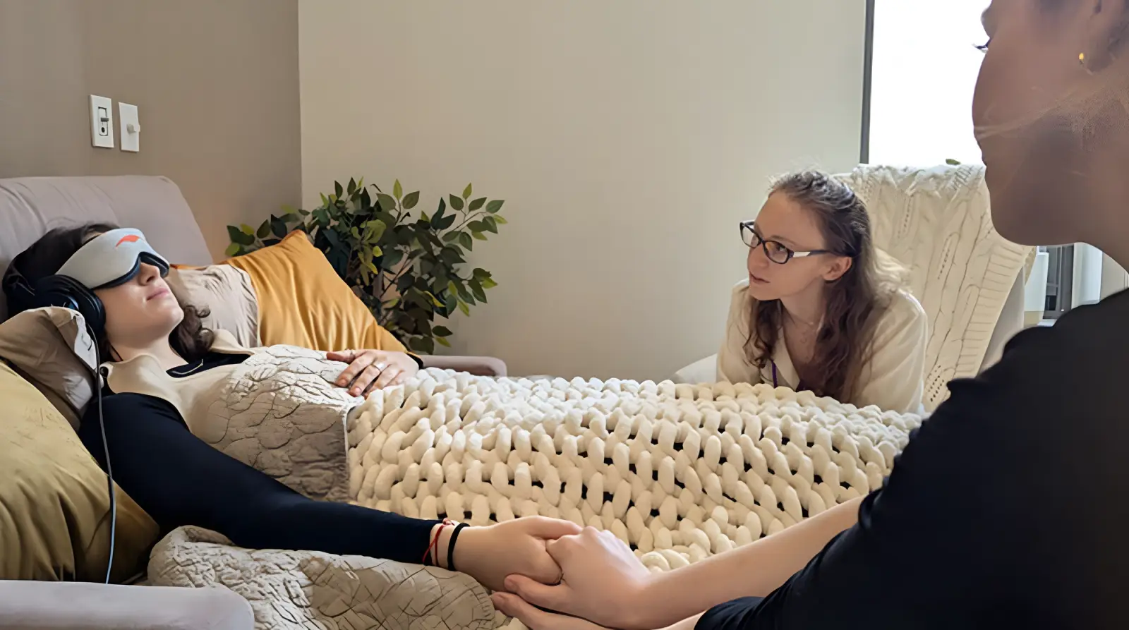 A therapist holds the hand and comforts a patient.